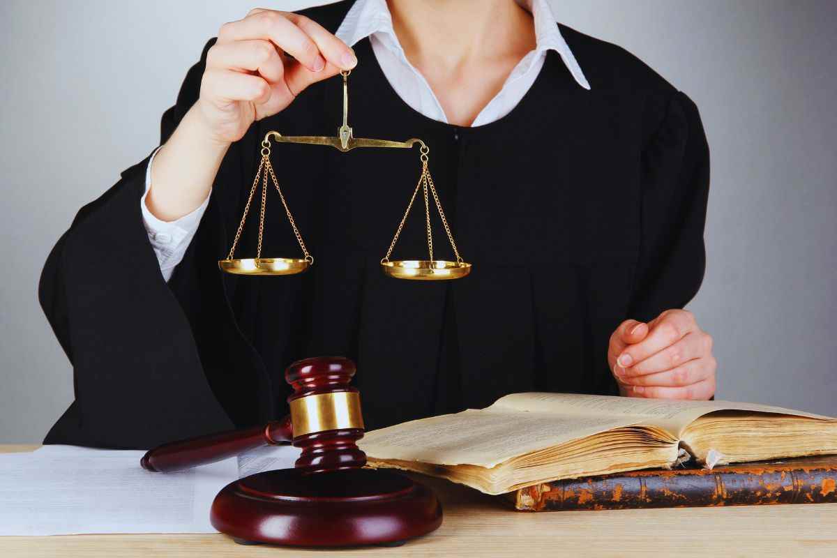 Giudice seduto alla scrivania che tiene in mano una bilancia