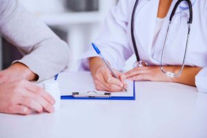 Medico che scrive un referto accanto al paziente