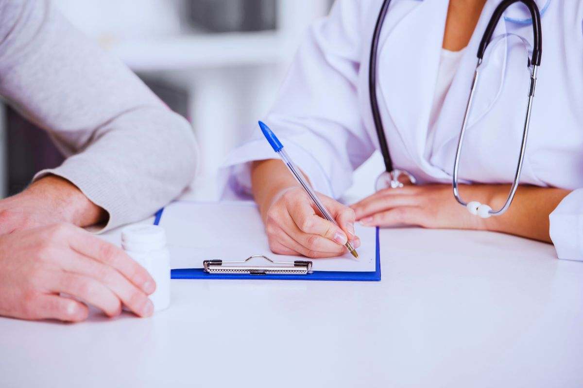 Medico che scrive un referto accanto al paziente