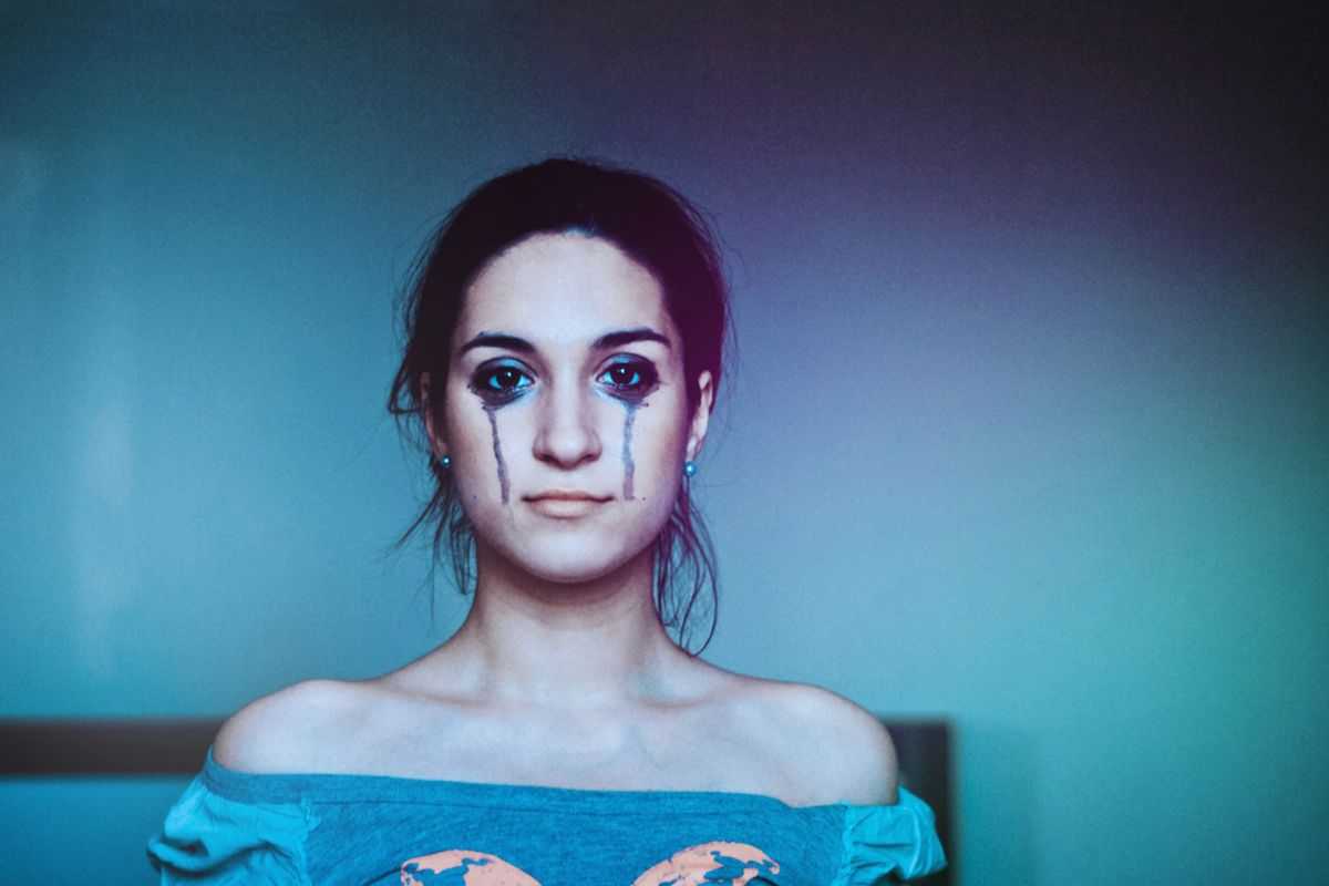 Ragazza con il viso sporcato dal trucco che cola sulle guance a causa delle lacrime