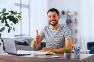 Ragazzo sorridente alla scrivania che mostra il pollice in alto