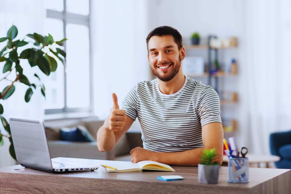 Ragazzo sorridente alla scrivania che mostra il pollice in alto