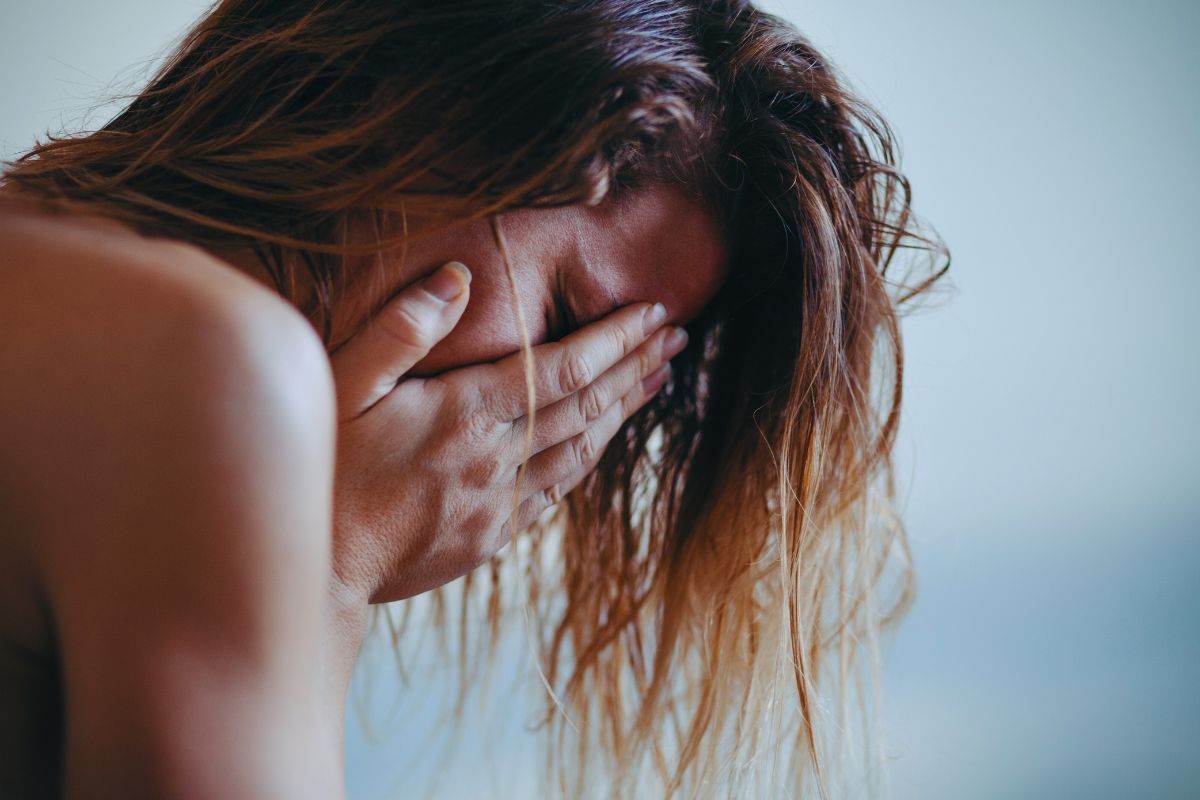 Donna in lacrime che si porta le mani sul viso