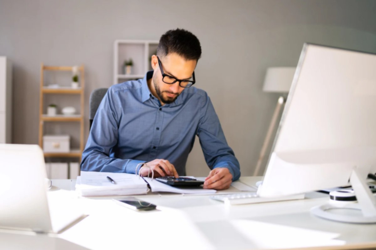 uomo che fa i calcoli seduto davanti al computer