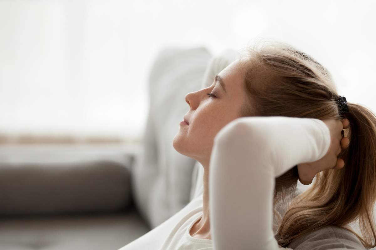 donna rilassata sul divano con mani dietro la nuca