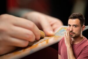 mano che gratta un gratta e vinci con uomo con mano vicino alla bocca