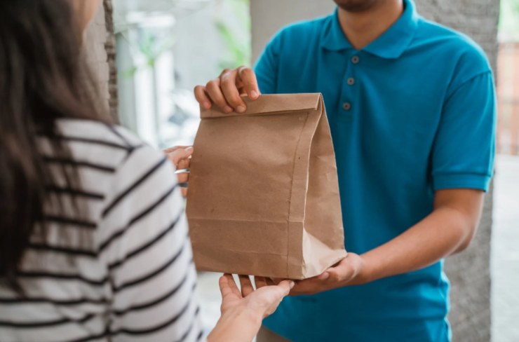 ragazzo che consegna un pacco con del cibo ad una donna