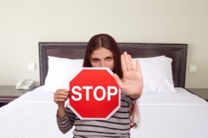 donna su letto bianco con segnale stop in mano